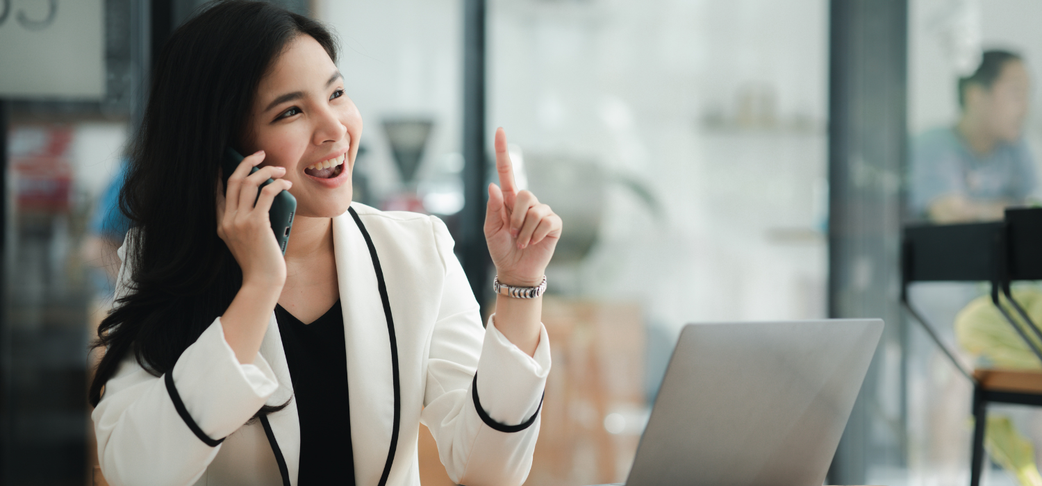 Woman on phone with laptop in a modern office setting